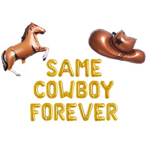 May include: A collection of gold foil balloons spelling "SAME COWBOY FOREVER" with a brown horse balloon and a brown cowboy hat balloon. The horse is rearing up on its hind legs. The cowboy hat has a black star.