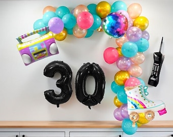 May include: A festive birthday balloon arrangement featuring a black "30" balloon set, a boombox, a roller skate, and a retro cell phone. The balloons are in various colors, including pink, blue, gold, and purple, creating a vibrant party atmosphere.