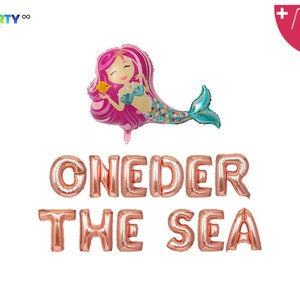 Op de afbeelding: Een set ros&eacute;gouden folieballonnen met de tekst "ONEDER THE SEA" en een roze en turquoise zeemeerminballon. De zeemeermin houdt een gele vis vast. Inclusief ballonzakje en touw.