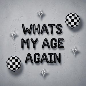 May include: Black balloon letters spell "WHAT'S MY AGE AGAIN" on a gray background. The balloons are surrounded by silver star-shaped balloons and two black and white checkered sphere balloons. The overall theme is a birthday or celebration.