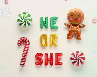 May include: Foil balloons spelling HE OR SHE in green, gold, and red. Includes a gingerbread person balloon, a red and white candy cane balloon, and two round peppermint candy balloons, all arranged with small snowflake and candy accents.