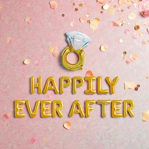 May include: A gold foil balloon spelling out "Happily Ever After" on a pink background. A diamond ring balloon is above the text. Scattered rose petals and confetti add to the celebratory theme.