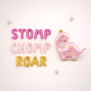May include: Pink dinosaur-shaped balloon with a gold crown, next to the words "STOMP CHOMP ROAR" in pink and gold balloon letters. Silver star-shaped balloons are scattered around the text and dinosaur.