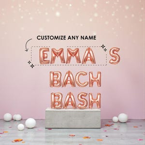 May include: Rose gold foil letter balloons spelling "EMMA'S BACH BASH" against a pink background. The text "CUSTOMIZE ANY NAME" is above the balloons. White balloons and confetti are scattered on the floor.