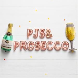 May include: A festive arrangement of foil balloons spelling "PJS & PROSECCO" in rose gold. Includes a champagne bottle and a champagne glass balloon. The bottle is green with gold accents, and the glass is gold. Scattered confetti adds to the celebratory theme.