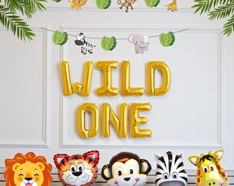 Könnte beinhalten: Dekorationsset für eine "Wild One" Geburtstagsfeier. Enthält goldfarbene Folienballons mit der Aufschrift "WILD ONE", tierförmige Folienballons und eine Girlande mit Tierausschnitten und grünen Blättern.