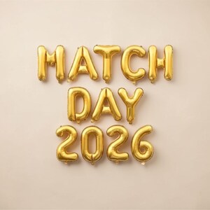 May include: Gold foil balloon letters spelling "MATCH DAY 2026" against a neutral background. The balloons are inflated and arranged to form the words and numbers, ideal for a celebratory event.