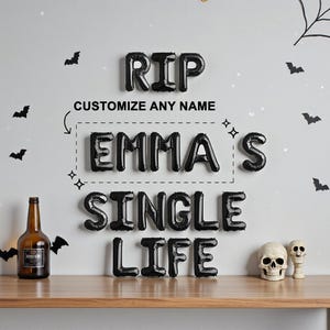May include: A Halloween-themed display with black balloon letters spelling "RIP EMMA'S SINGLE LIFE." Includes a brown bottle, skull decorations, and bat and spiderweb wall decals. The text "CUSTOMIZE ANY NAME" is also present.