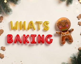 May include: Gold foil balloons spelling WHATS and red foil balloons spelling BAKING arranged with a brown gingerbread man foil balloon, surrounded by small gingerbread cookie cutouts and green pine branches on a light cream background.