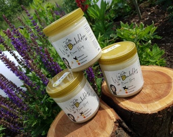Puede incluir: Tres tarros de vidrio de miel con tapas doradas. Los tarros están etiquetados con "Wabenheldin" y "Bienen Honig". Los tarros están sobre una superficie de madera.