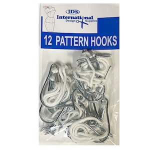 May include: A package of 12 white pattern hooks with silver metal hooks. The package is labeled "IDS International Design & Supplies 12 Pattern Hooks".