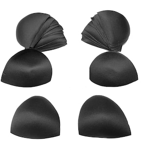 May include: Four black bra pads, two are folded and stacked, and two are laid flat. The pads are made of a soft, smooth fabric.