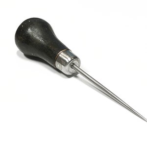 May include: A black wooden handled awl with a silver metal tip and a long, thin, pointed needle.