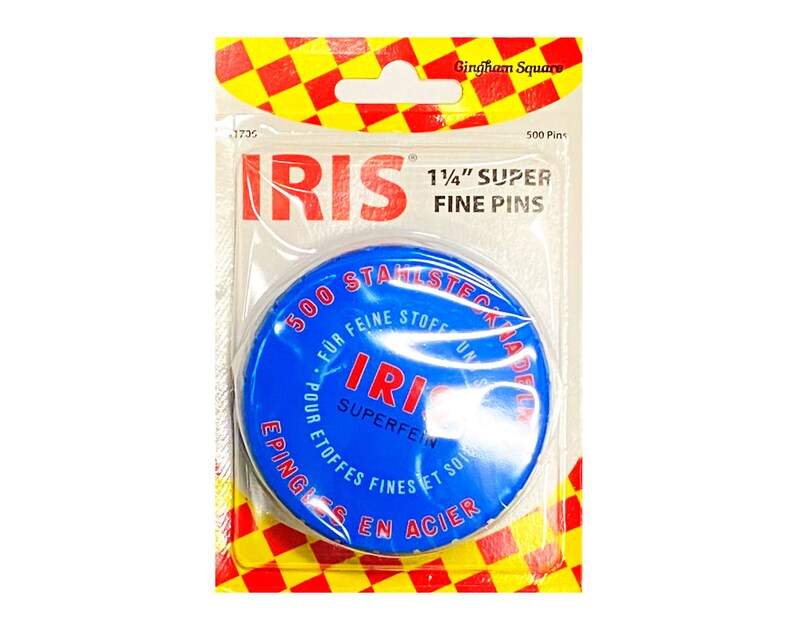 Peut inclure: Une bo&icirc;te ronde bleue et rouge de 500 &eacute;pingles en acier inoxydable super fines de 1 1/4 pouce. La bo&icirc;te porte le texte "IRIS" en lettres rouges et blanches et le texte "500 STAINLESS STEEL PINS" en lettres blanches sur fond bleu.