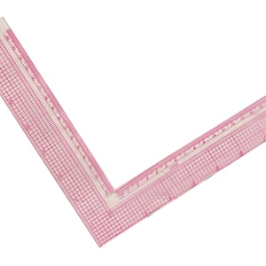 May include: A white plastic 12-inch ruler with a 90-degree angle. The ruler has a grid pattern and inch markings. The ruler is made by Westcott.
