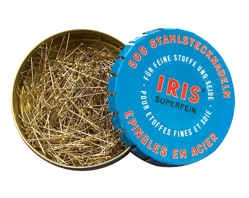 Peut inclure: Une bo&icirc;te en m&eacute;tal bleue avec une &eacute;tiquette blanche et rouge contenant 500 &eacute;pingles &agrave; coudre en acier. L'&eacute;tiquette indique "500 Stahlstecknadeln f&uuml;r feine Stoffe und Seide - Iris Superfein - Epingles en acier pour &eacute;toffes fines et soie".