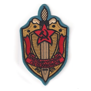 May include: A teal embroidered patch with a gold shield, a red star with a hammer and sickle, and a sword. The text on the ribbon reads "ДЛЯ ВСЕЙ СОТРУДНИ ТОВСЕХ ЖИТЕЛЬСТВ".