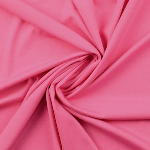 May include: A close-up of a soft, pink fabric with a smooth texture. The fabric is folded and draped, creating a flowing, elegant look.