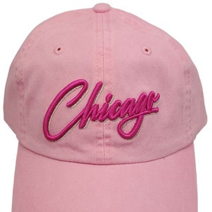 May include: A pink baseball cap with the word "Chicago" embroidered in pink and white.