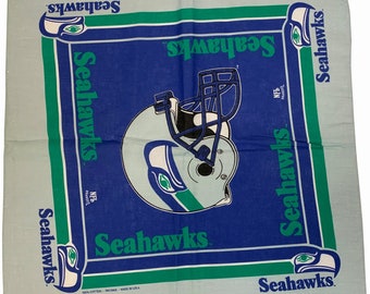 Puede incluir: Un bandana azul y verde con el logotipo de los Seattle Seahawks y las palabras "Seahawks" repetidas varias veces. El bandana está hecho de 100% algodón y está impreso en los Estados Unidos.