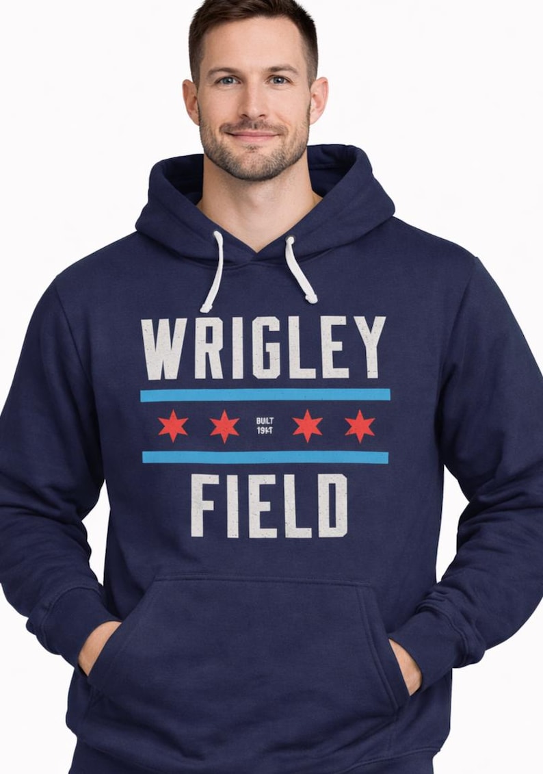 May include: Navy blue hoodie with the text "WRIGLEY FIELD" in white block letters. The design includes red stars and blue stripes, with "BUILT 1914" in the center. The hoodie has a drawstring hood and a front pocket.