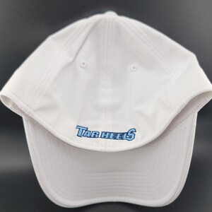 May include: White baseball cap with the text "Tar Heels" embroidered in light blue. The cap has a curved brim and a structured crown. The hat is made of a lightweight, breathable material.