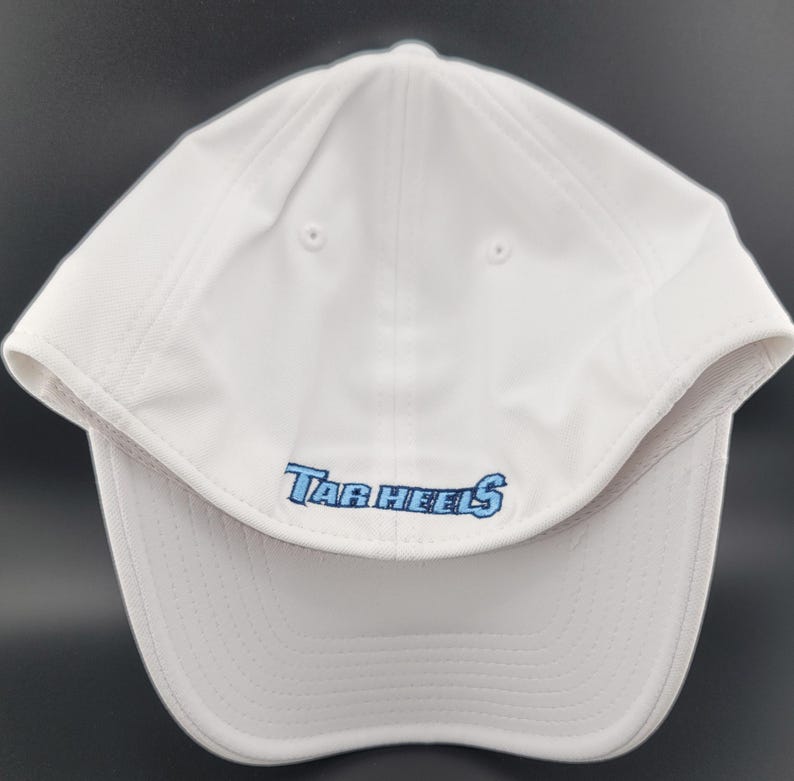 May include: White baseball cap with the text "Tar Heels" embroidered in light blue. The cap has a curved brim and a structured crown. The hat is made of a lightweight, breathable material.
