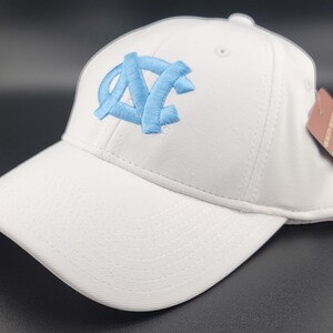 May include: White baseball cap with a curved brim. The cap features a light blue embroidered logo on the front. A tag is attached to the side. The cap is made of a textured fabric.