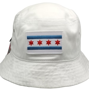 May include: White bucket hat with a Chicago flag patch on the front. The flag is blue, white, and red with six red stars.