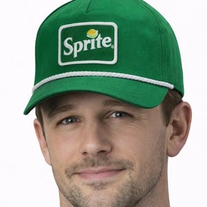 May include: Green cap with the Sprite logo in a white-bordered rectangle. The logo features the word "Sprite" in white, with a lemon graphic. A white rope detail accents the brim. The cap is worn by a person.