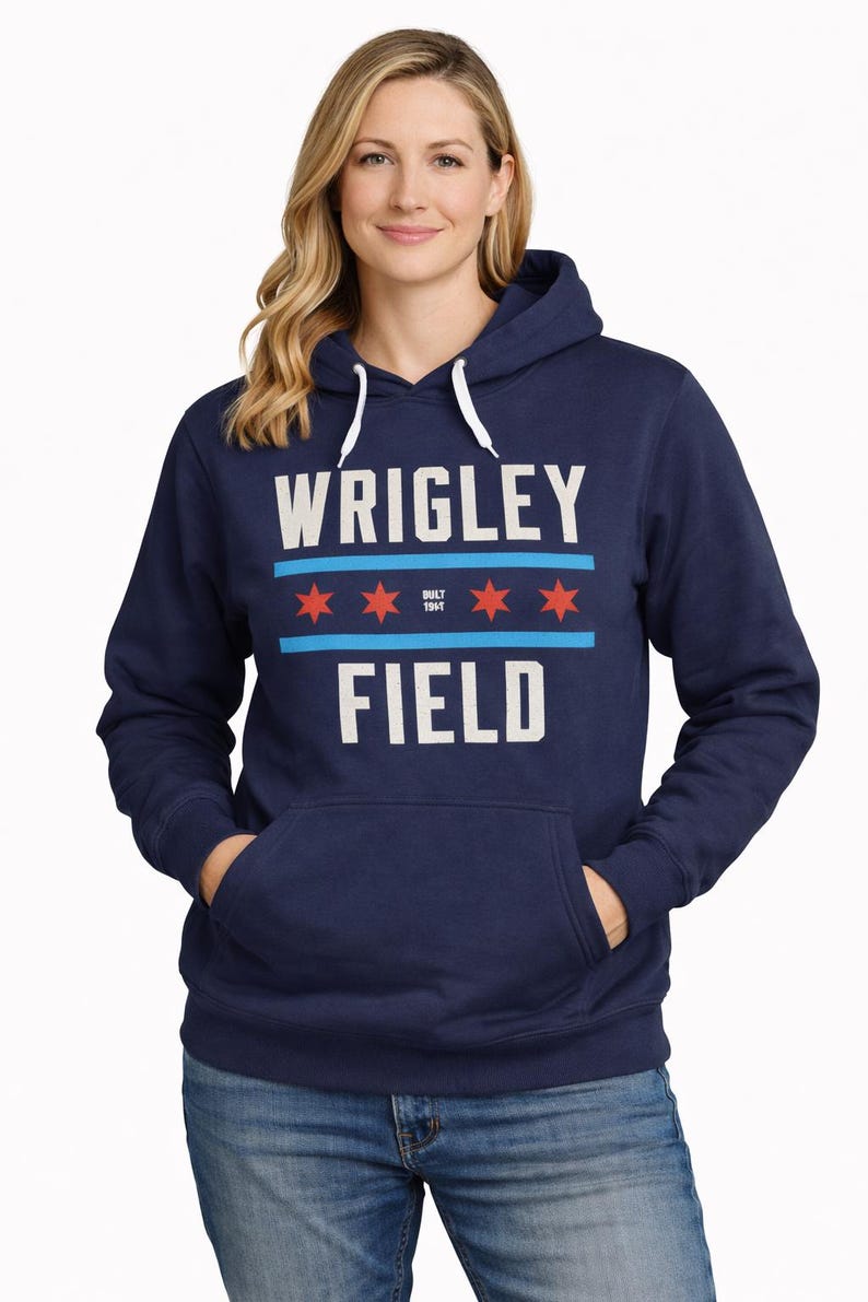 May include: Navy blue hooded sweatshirt with the text "WRIGLEY FIELD" in white block letters. The design includes blue stripes and red stars. The sweatshirt has a front pocket and a white drawstring hood.