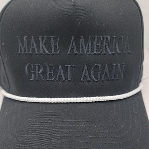 May include: Black baseball cap with a white rope trim and the text "MAKE AMERICA GREAT AGAIN" embroidered in black.