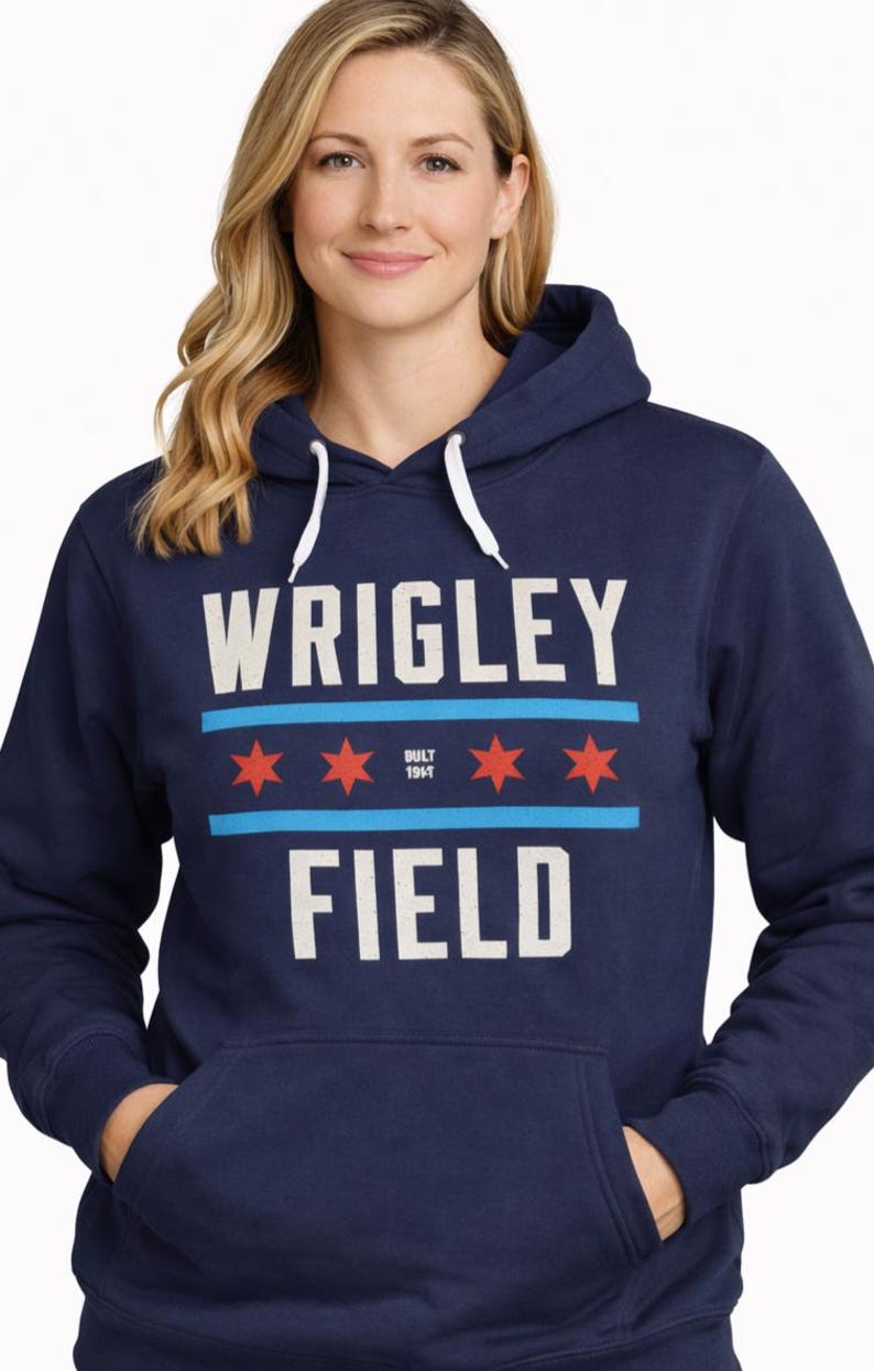 May include: Navy blue hooded sweatshirt with the text "WRIGLEY FIELD" in white block letters. The design includes a light blue stripe with three red stars, and the text "BUILT 1914". The sweatshirt has a front pocket and white drawstrings.