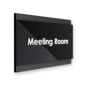 May include: Black sign with a wood frame and the text "Meeting Room" in white raised letters.
