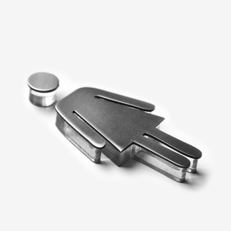 May include: A silver metal cutout of a person, with a round head, standing on a clear acrylic base.