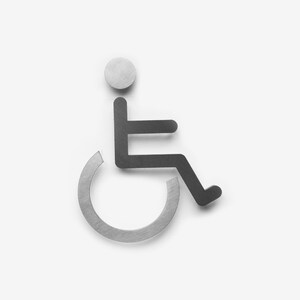 May include: A silver and black wheelchair accessibility symbol. The symbol is a stylized image of a person in a wheelchair.