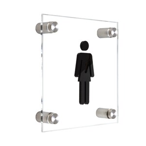Puede incluir: Una silueta negra de una persona en un letrero de acrílico transparente con cuatro soportes plateados.