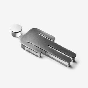 Op de afbeelding: Een zilveren metalen uitsnijding van een persoon met een rond hoofd. De uitsnijding ligt op een wit oppervlak.