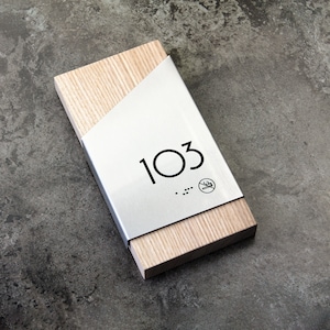 May include: A wooden sign with a silver metal plate that says "103" with braille dots and a no smoking symbol.