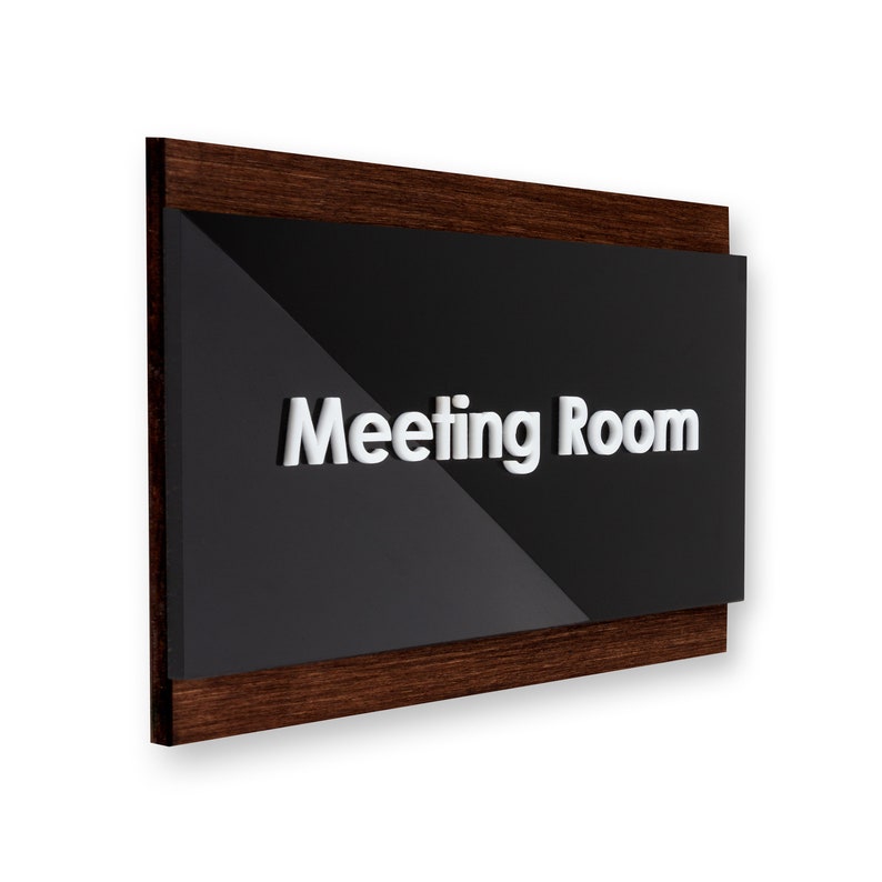 May include: A dark brown wooden sign with a black acrylic panel that says "Meeting Room" in white raised letters.