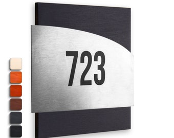 May include: A black and silver house number sign with the number 723 on a silver plate. The sign is made of wood and metal.