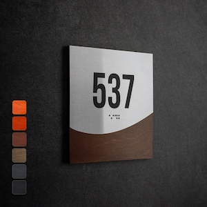 May include: A silver and brown metal door sign with the number 537 and braille dots.