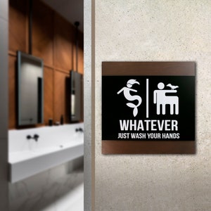 May include: A black and white sign with a wooden frame. The sign has a mermaid and a man on it. The text on the sign reads "Whatever Just Wash Your Hands".