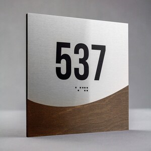 May include: A silver and brown room number sign with the number 537 in black lettering and braille dots below.