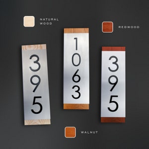 May include: Three house numbers, 1063, 395, and 395, are displayed on metal plaques with wood trim. The plaques are available in natural wood, walnut, and redwood.