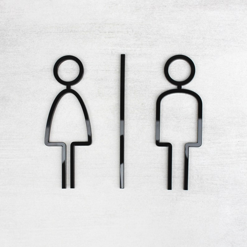 Puede incluir: Esquema en blanco y negro de un s&iacute;mbolo de ba&ntilde;o para hombres y mujeres con una l&iacute;nea vertical que los separa.