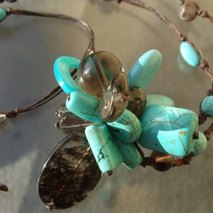 Peut inclure: Un collier de perles turquoise et brun avec un grand pendentif turquoise multi-facettes. Le collier est fait de cordon de cuir et présente une variété de perles turquoise et brunes.