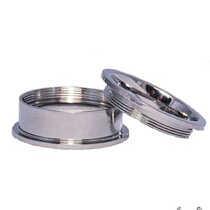 May include: Two silver metal rings, one larger than the other, with a threaded edge. The smaller ring is placed on top of the larger ring. The rings are for cremation jewelry.
