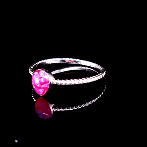 May include: A silver ring with a pink opal gemstone. The ring has a twisted band.