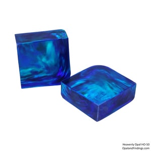 May include: Two blue and green opal cabochons, one is square and the other is rectangular, with a rounded edge. The opals are translucent and have a swirling pattern.
